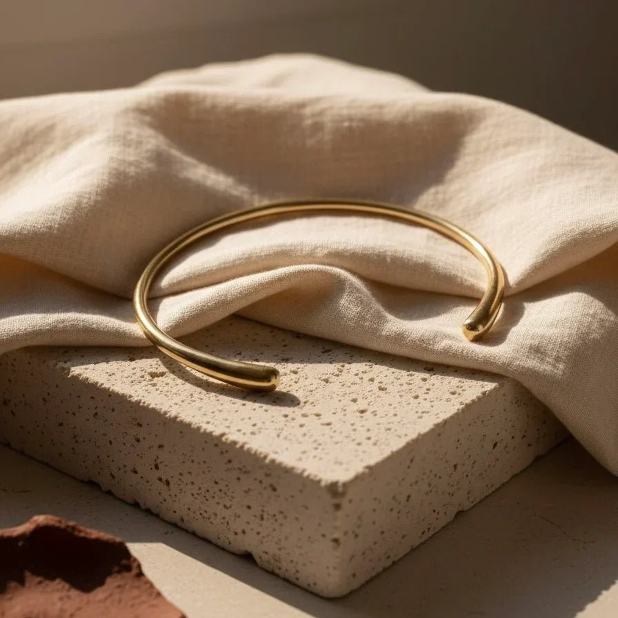Gold bracelet on a textured beige surface