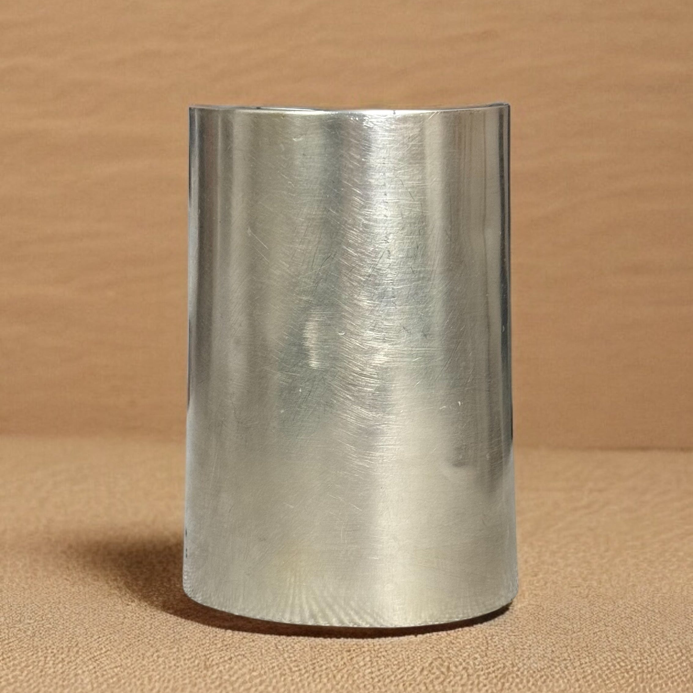Metallic cylindrical object on a beige background