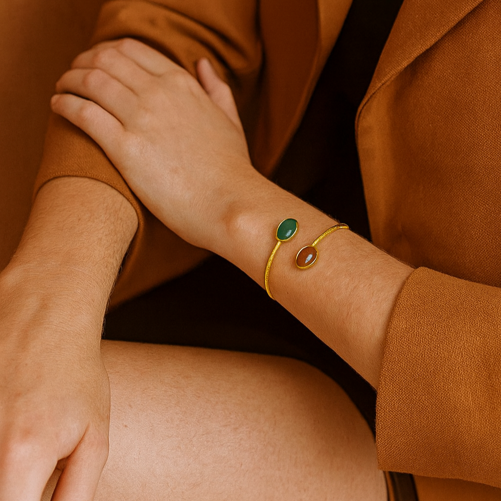 Close-up of a person wearing a gold bracelet with green gemstones, holding another person's hand.