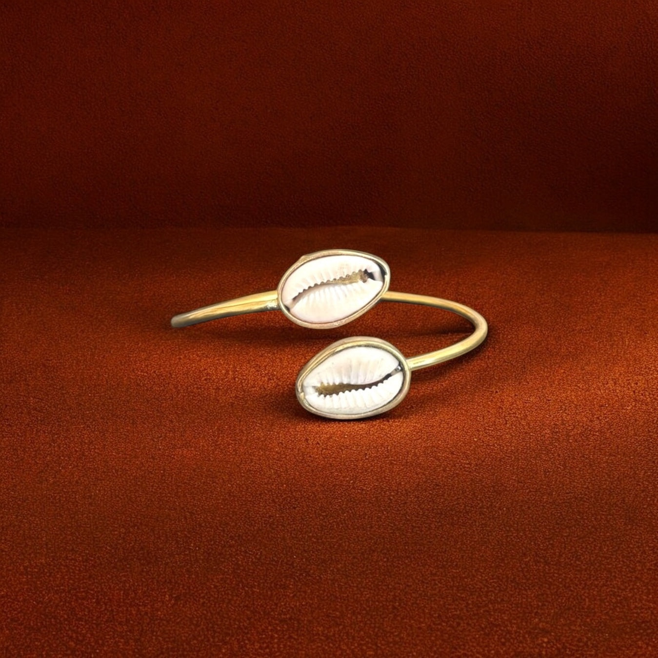 Gold bangles with shell design on a brown background