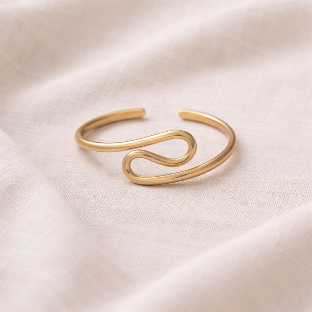 Gold bracelet on a light pink fabric background