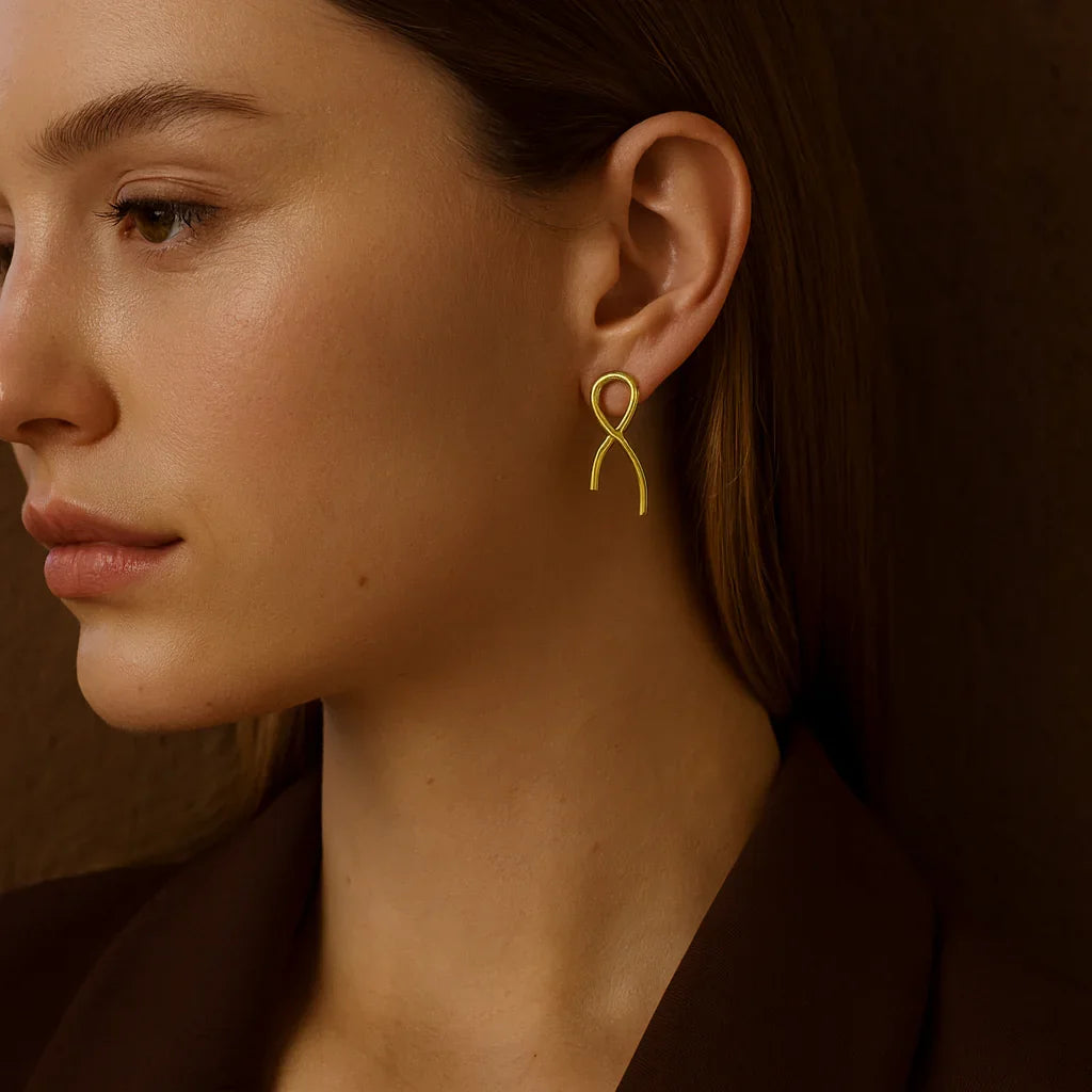 Close-up of a woman wearing a gold earring against a brown background