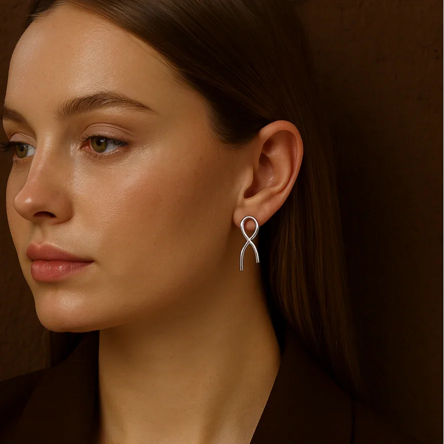 Close-up of a woman wearing a silver earring against a brown background