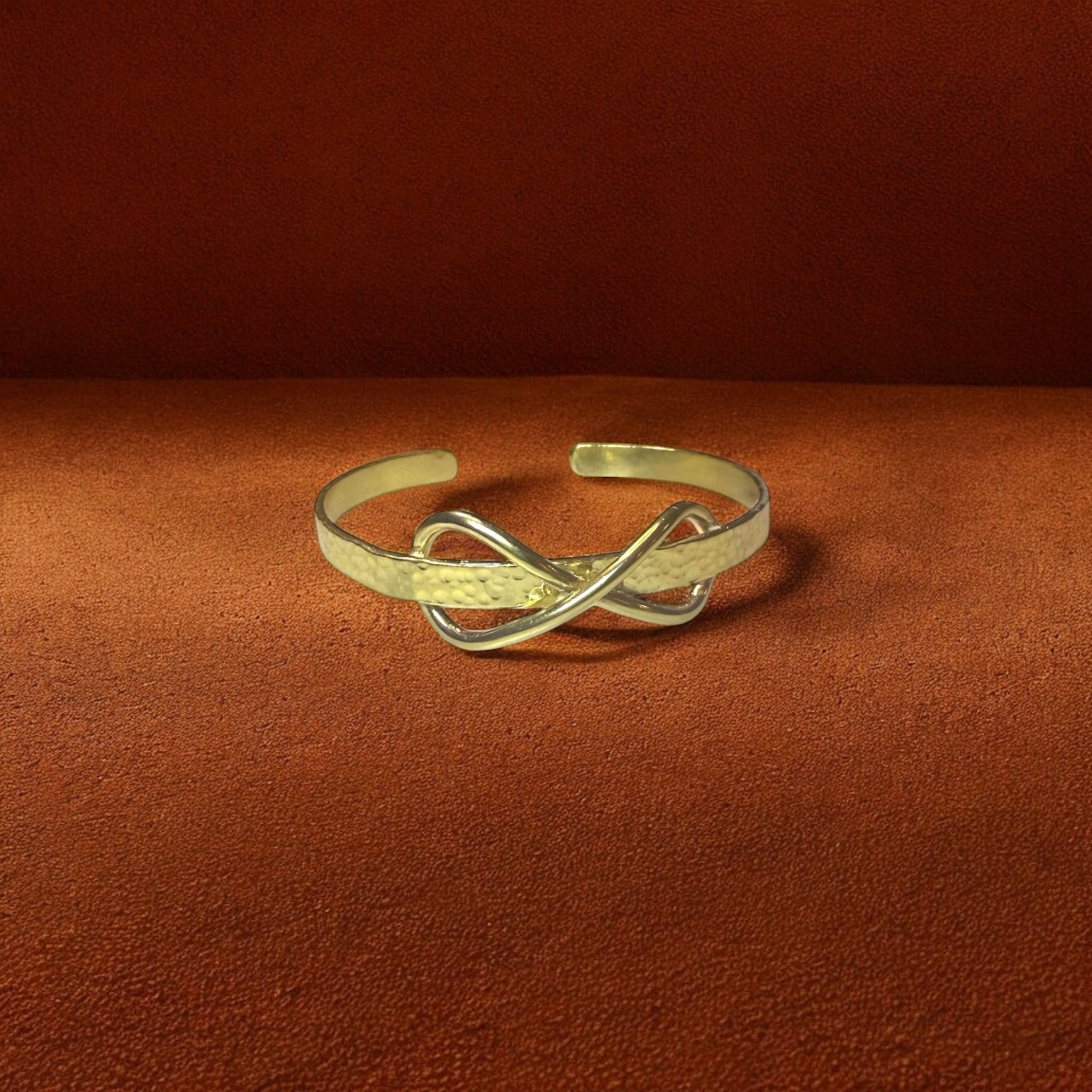 Gold bracelet with an infinity design on a brown background