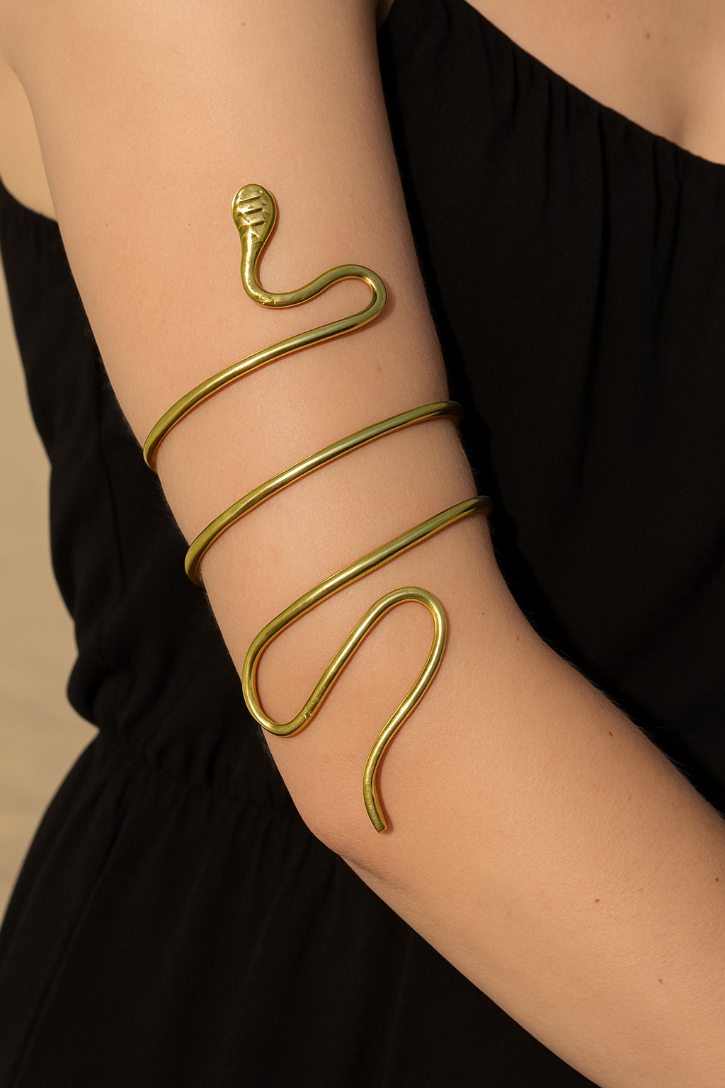 Gold snake-shaped bracelet on a person's wrist against a black background