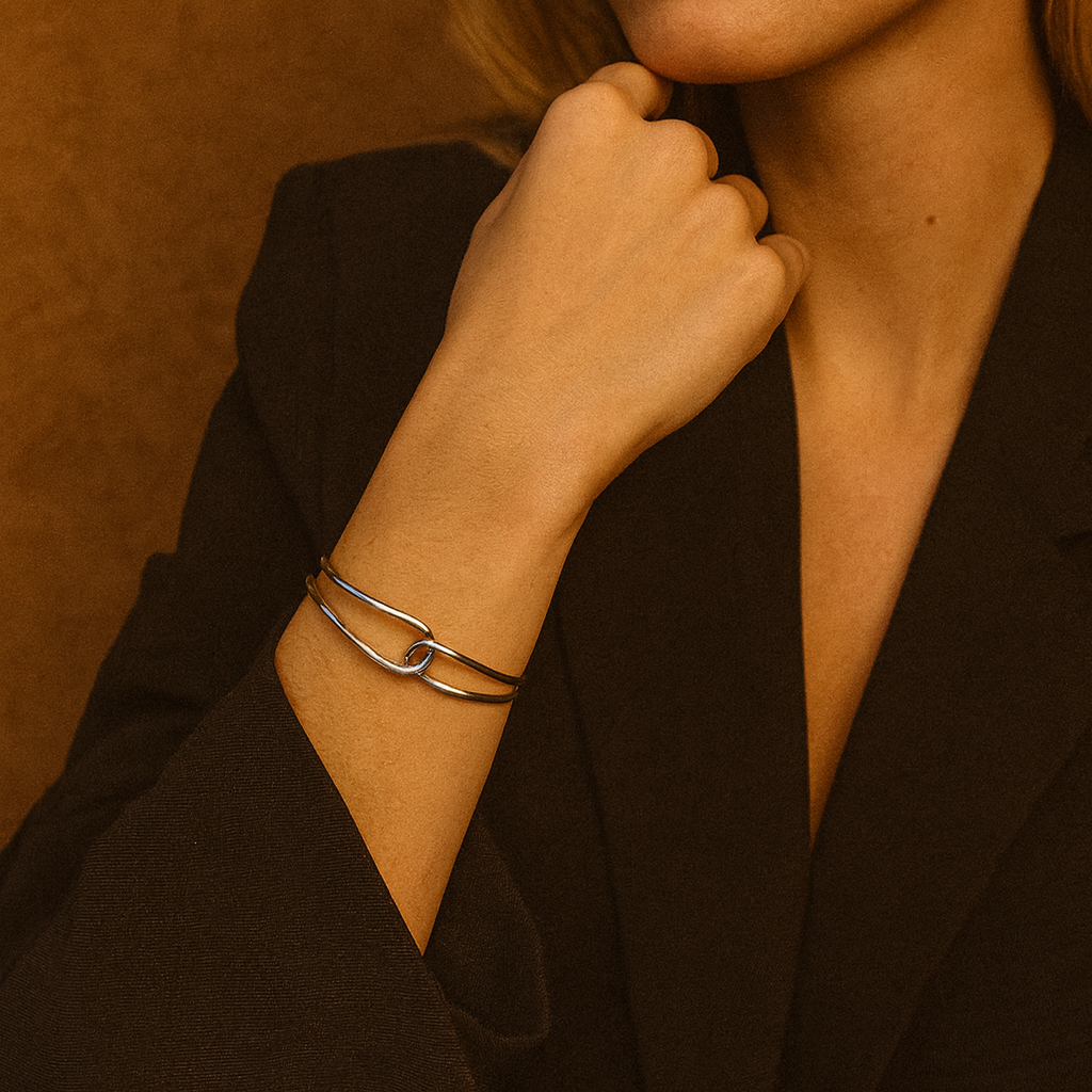 Woman wearing a black outfit with a gold bracelet against a warm brown background