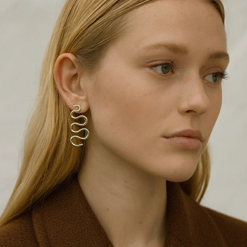 Woman wearing a gold spiral earring with a neutral background
