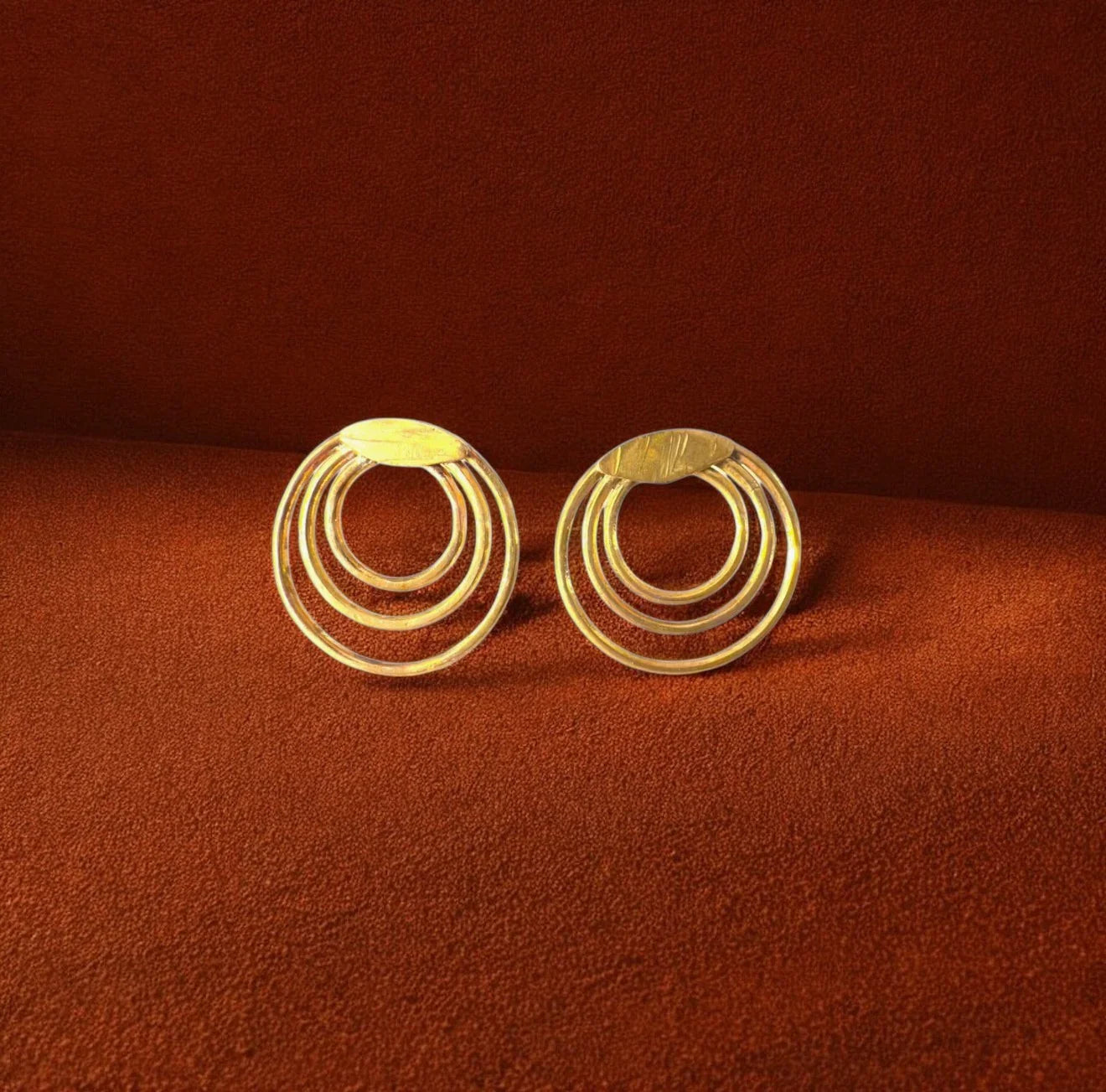 Pair of gold hoop earrings on a brown background