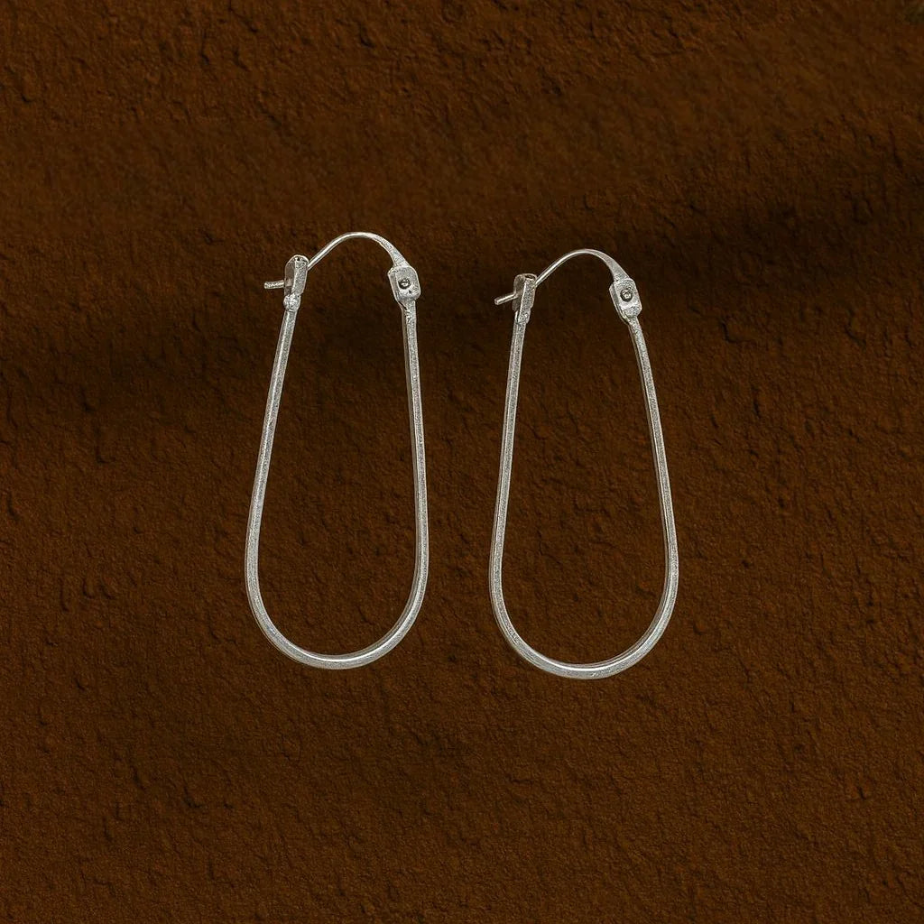 Silver hoop earrings on a brown textured background