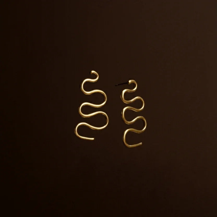 Gold spiral earrings on a dark background