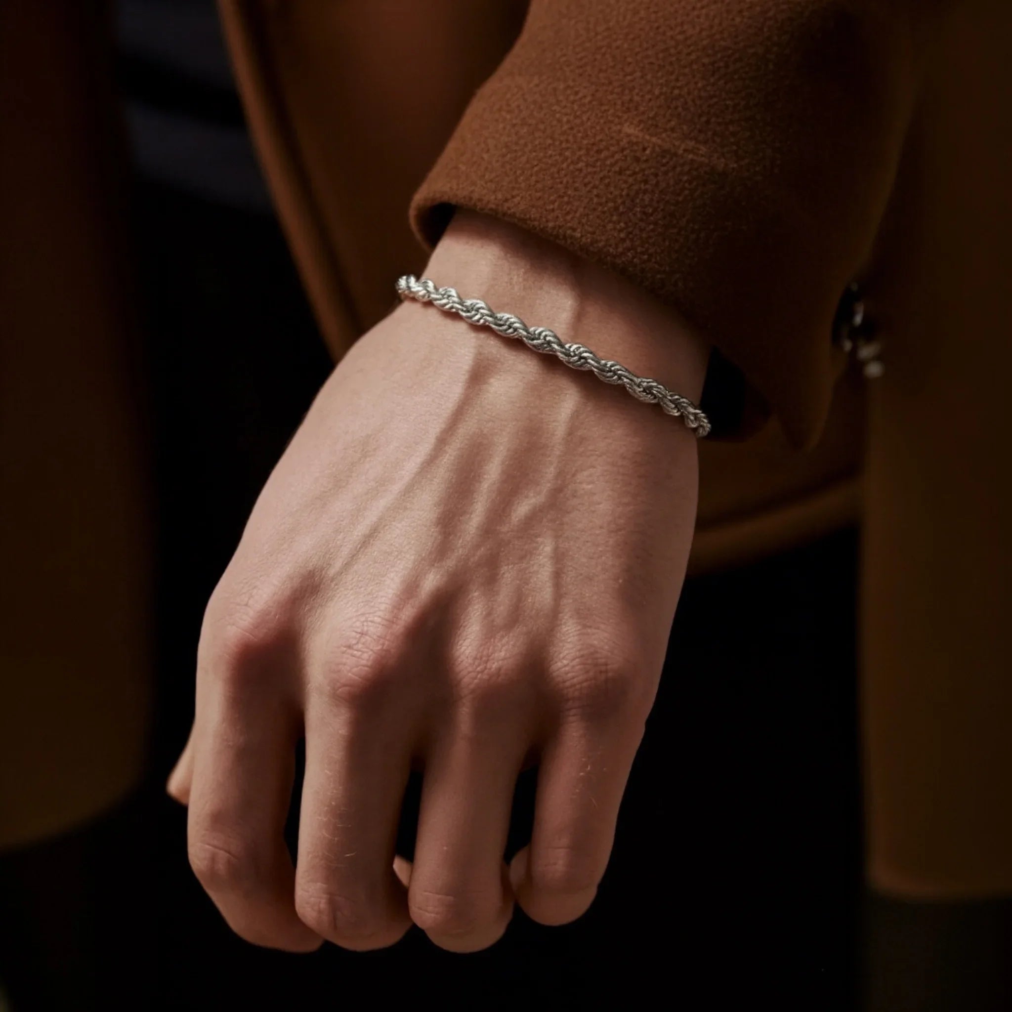 Hand wearing a silver bracelet with a blurred background