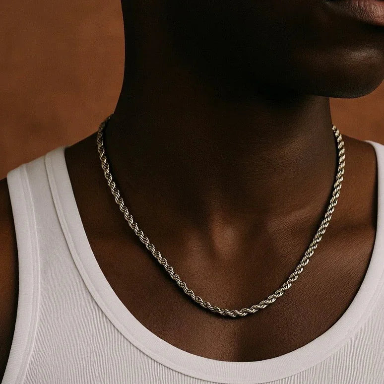 Person wearing a silver chain necklace against a neutral background