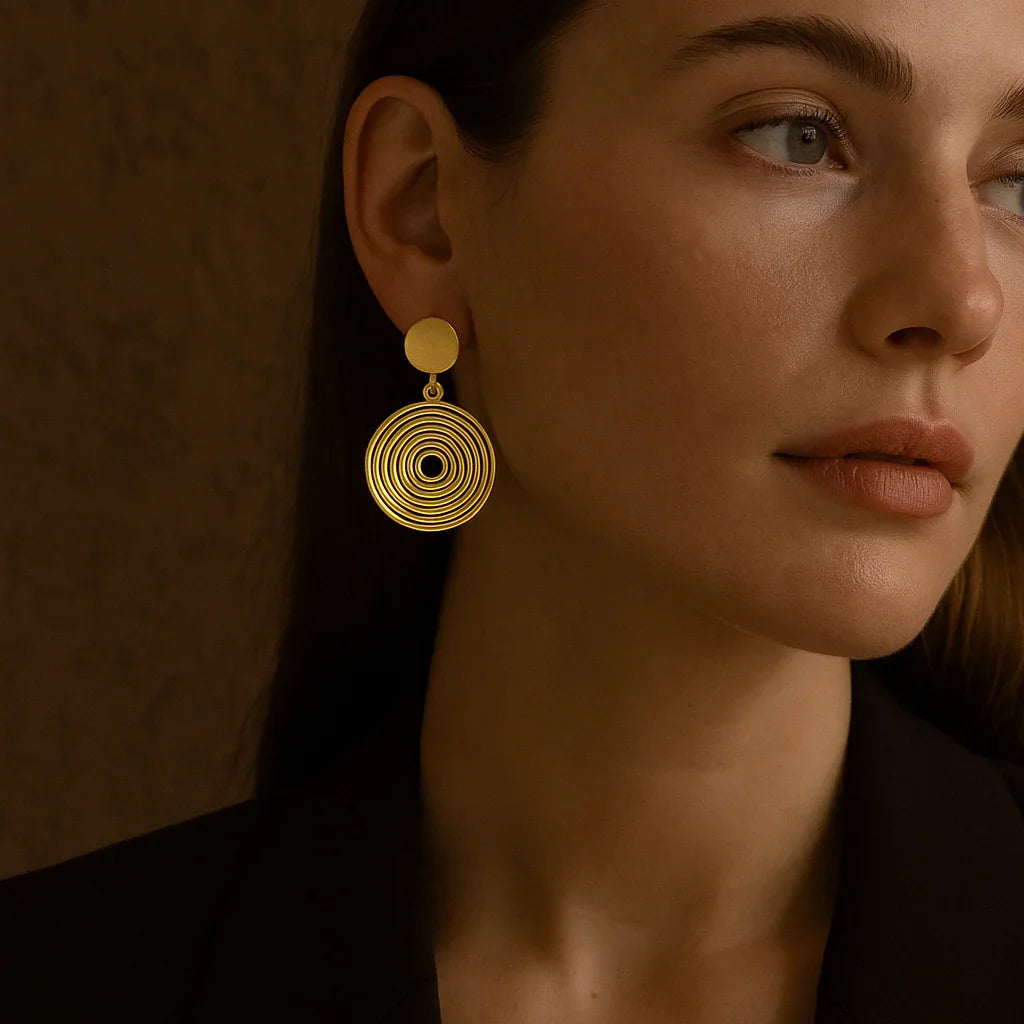 Woman wearing gold earrings against a warm brown background