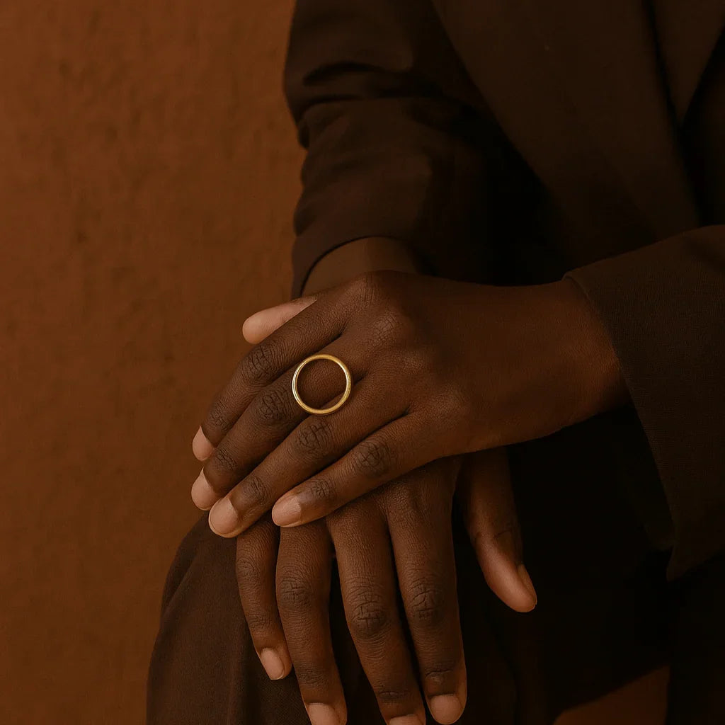 Person wearing a gold ring on a brown background