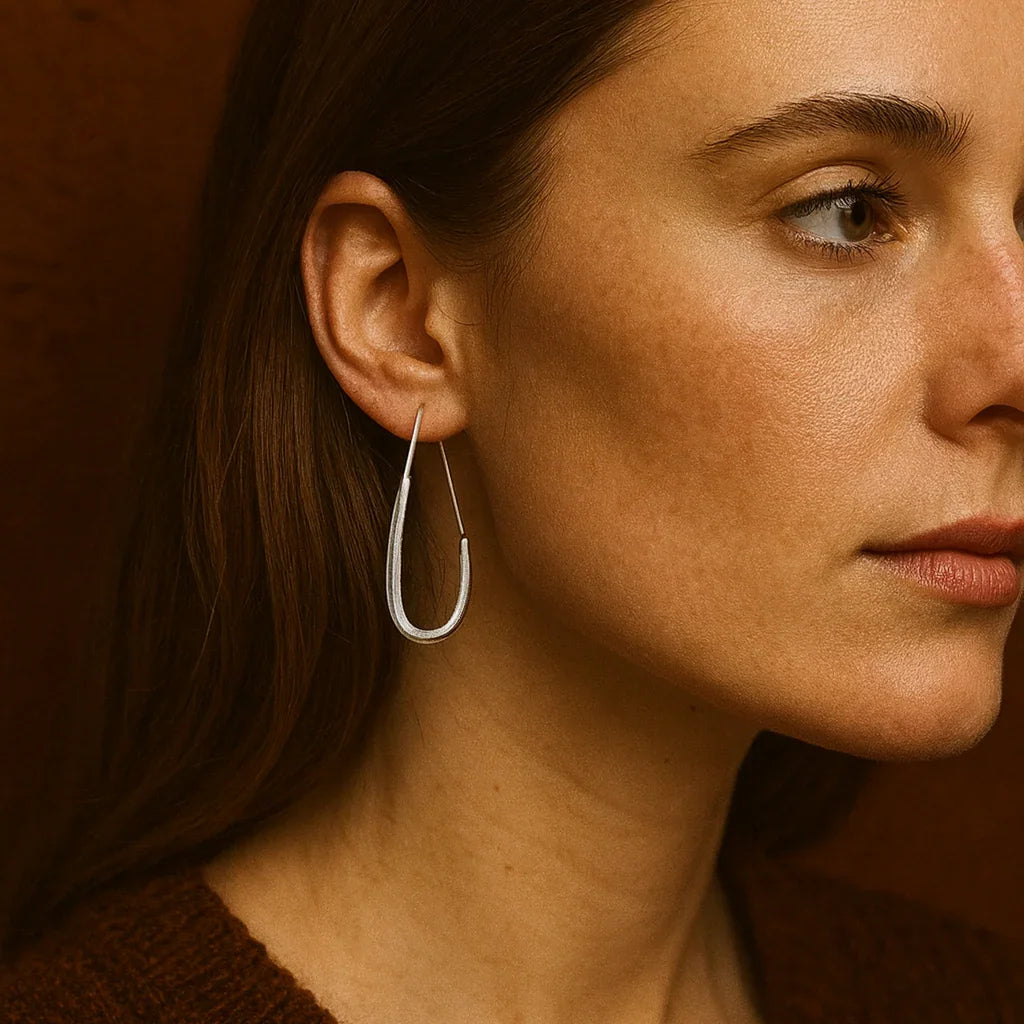 Close-up of a woman wearing a silver hoop earring against a brown background