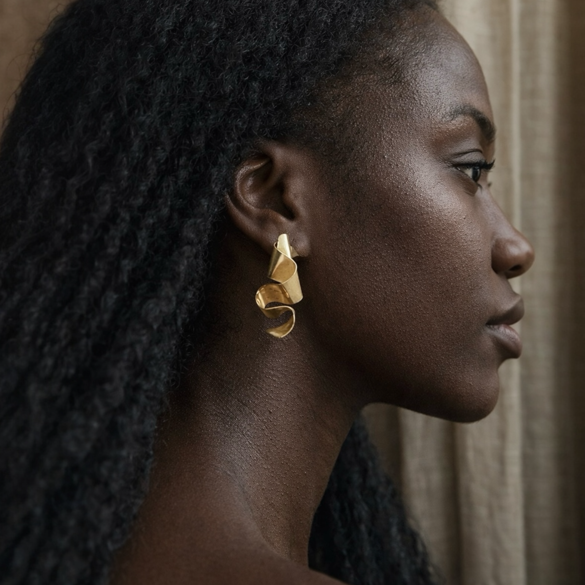 Woman wearing gold earrings with a neutral background