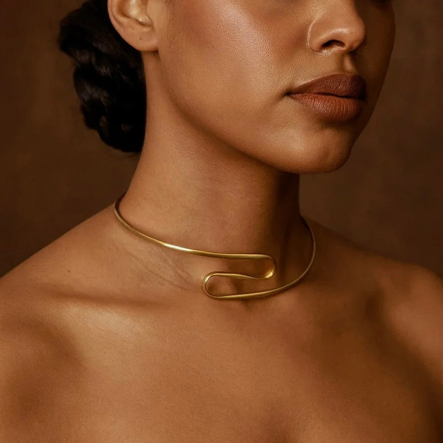 Close-up of a person wearing a gold necklace against a brown background