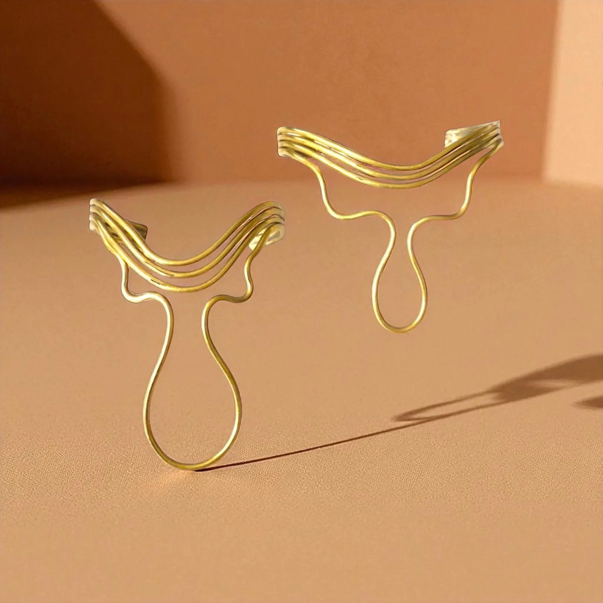 Two gold face masks on a beige background