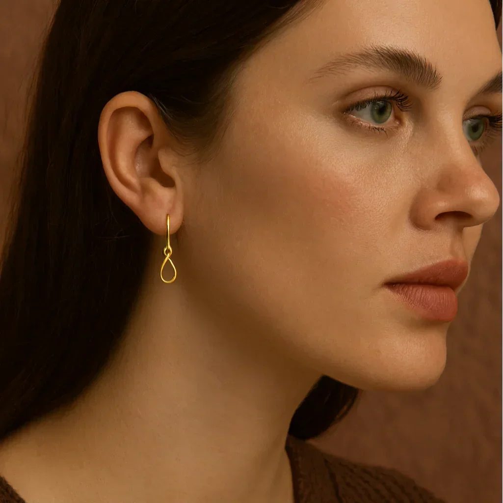 Close-up of a woman wearing a gold earring against a brown background