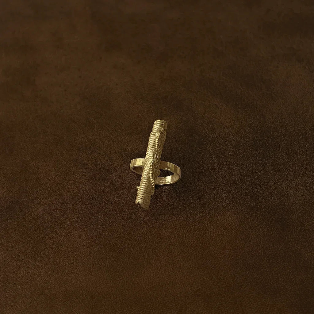 Gold ring with textured design on a brown background