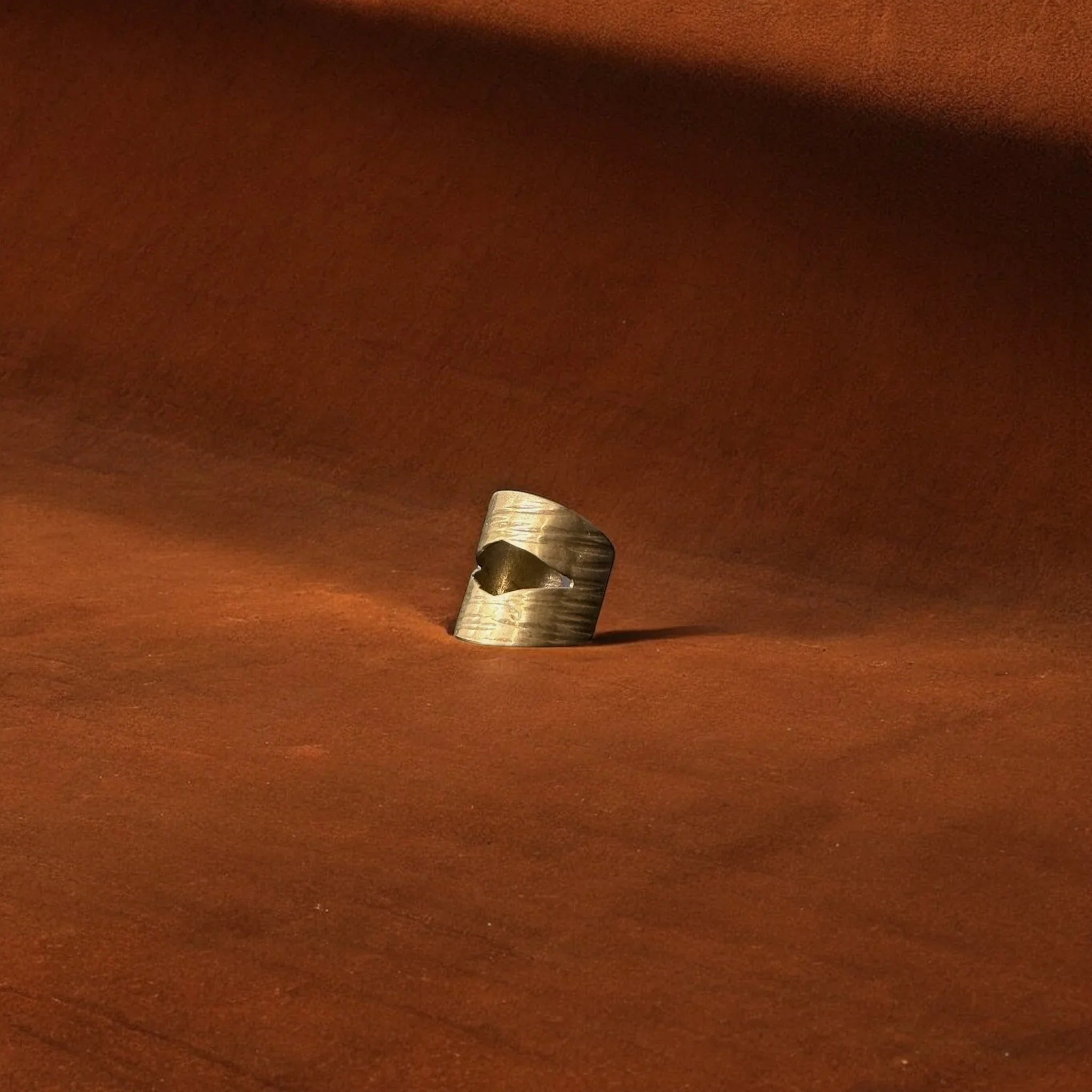 Gold ear cuff on a brown fabric background
