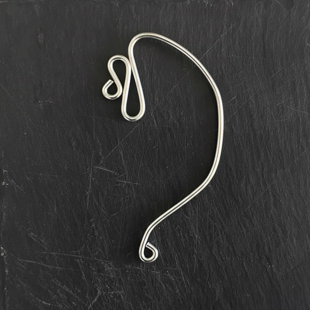 Silver wire earring on a black textured background