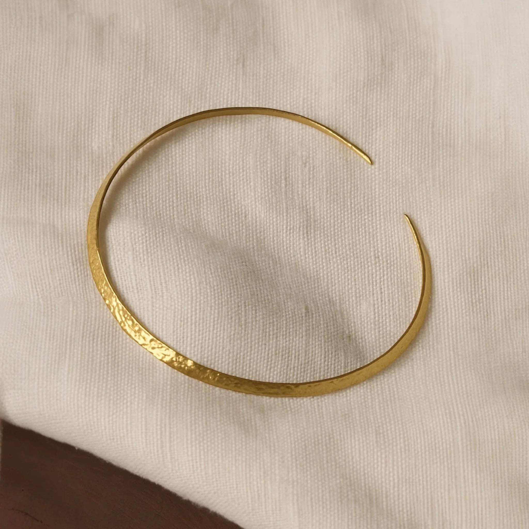 Gold bracelet on a beige fabric background