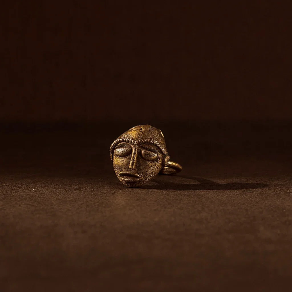 Bronze face pendant on a dark brown background