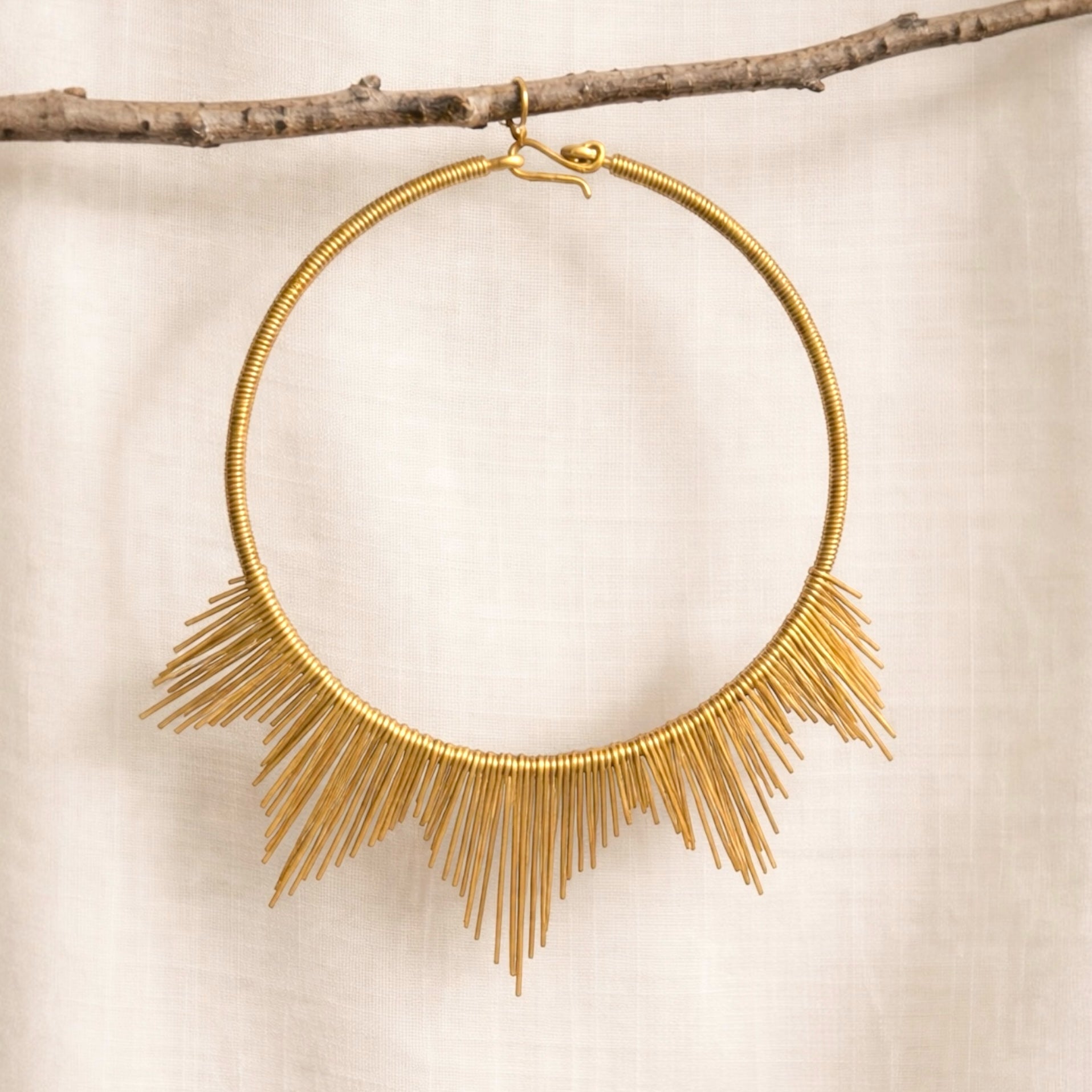 Gold necklace with fringe details on a beige background