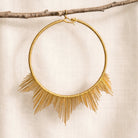Gold necklace with fringe details on a beige background
