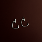 Pair of silver earrings on a dark brown background