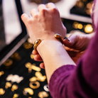 Close-up of a hand wearing a gold bracelet with blurred lights in the background