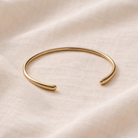 Gold bracelet on a soft beige fabric background