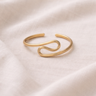 Gold bracelet on a light pink fabric background