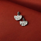 Silver earrings on a red fabric background
