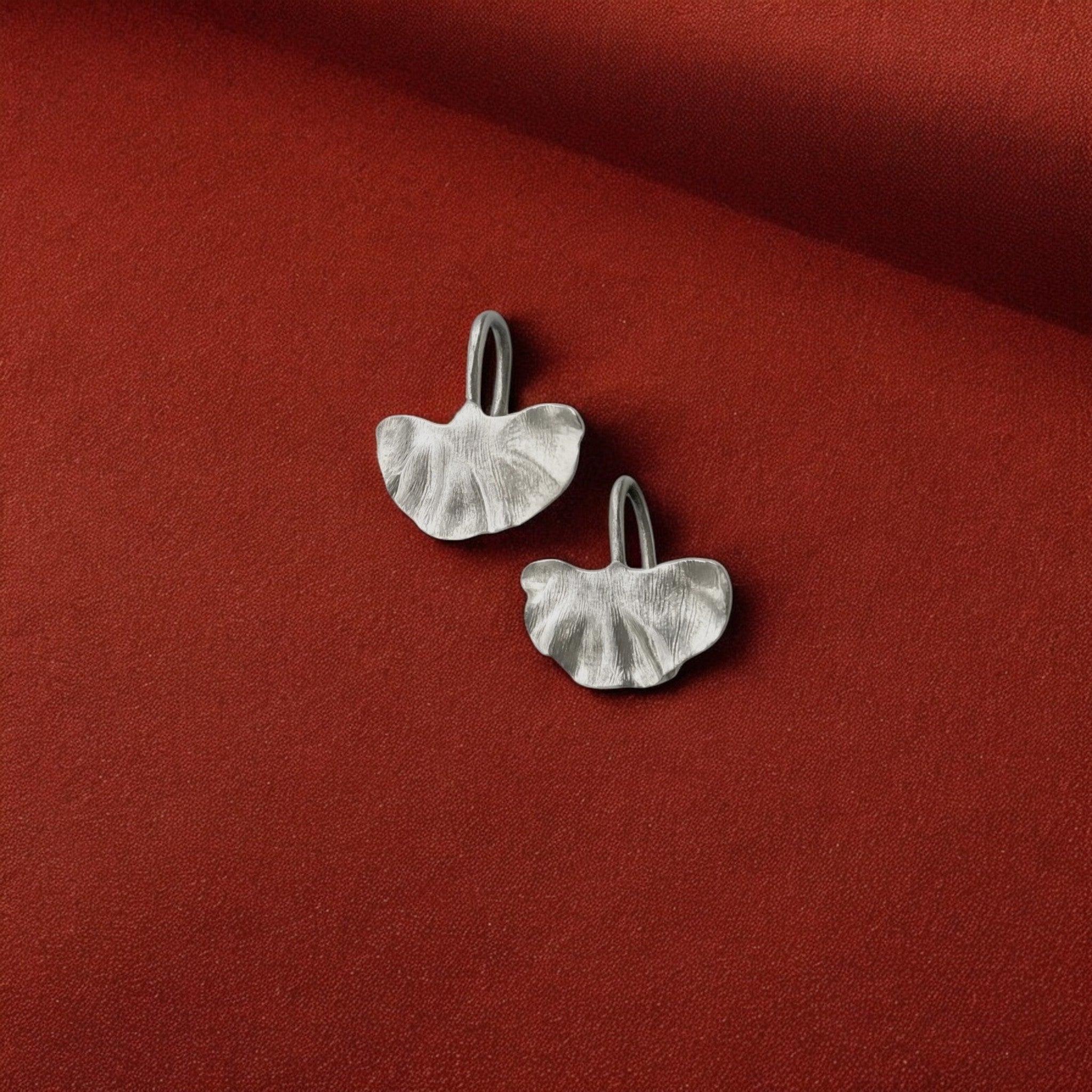 Silver earrings on a red fabric background