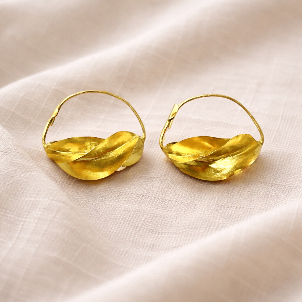 Pair of gold hoop earrings on a beige fabric background