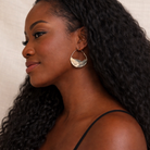 Woman wearing large hoop earrings with a neutral background