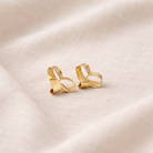 Pair of gold earrings on a beige fabric background