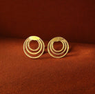 Pair of gold hoop earrings on a brown background