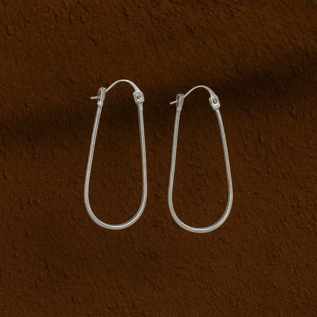 Silver hoop earrings on a brown textured background