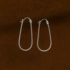 Silver hoop earrings on a brown textured background