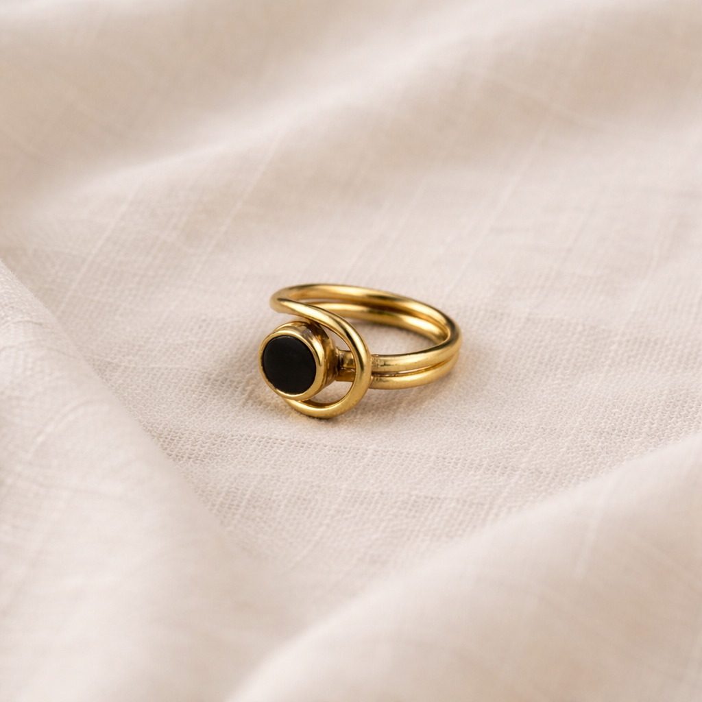 Gold ring with a black gemstone on a beige fabric background