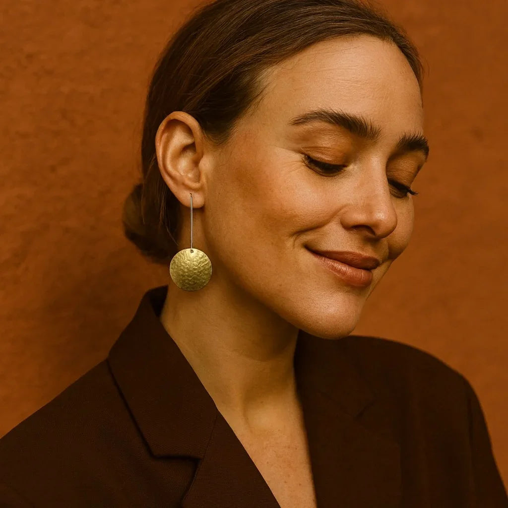 Woman wearing gold earrings against a warm brown background