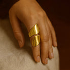 Gold ring on a person's finger with a neutral background