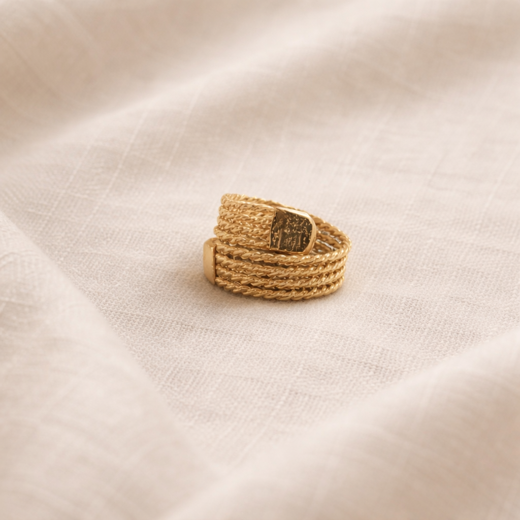 Gold braided ring with a button clasp on a beige fabric background