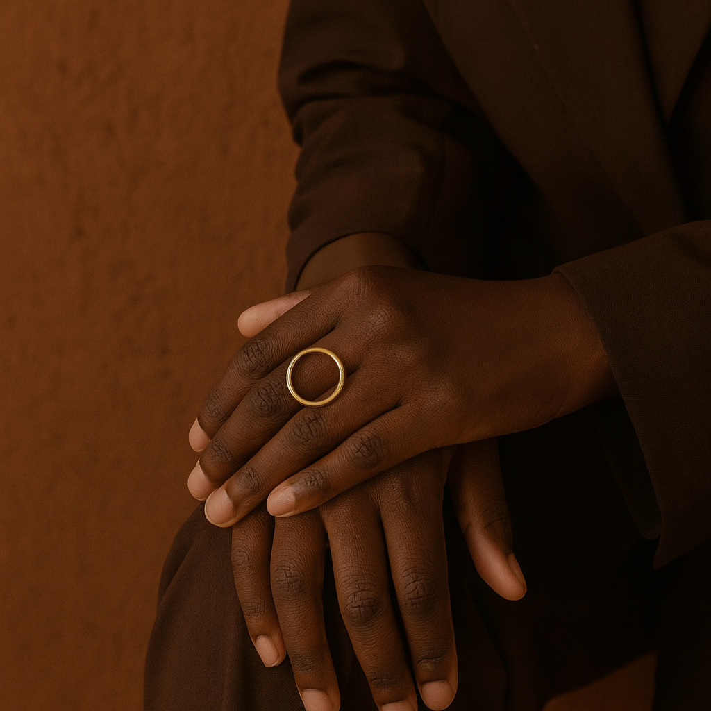 Person wearing a gold ring on a brown background