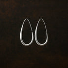 Pair of silver hoop earrings on a dark textured background
