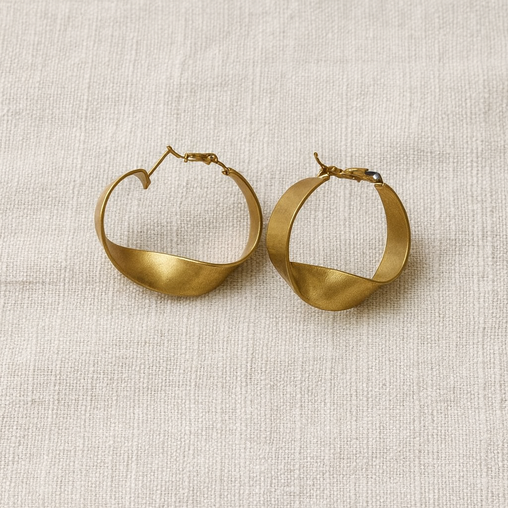 Pair of gold hoop earrings on a textured beige surface