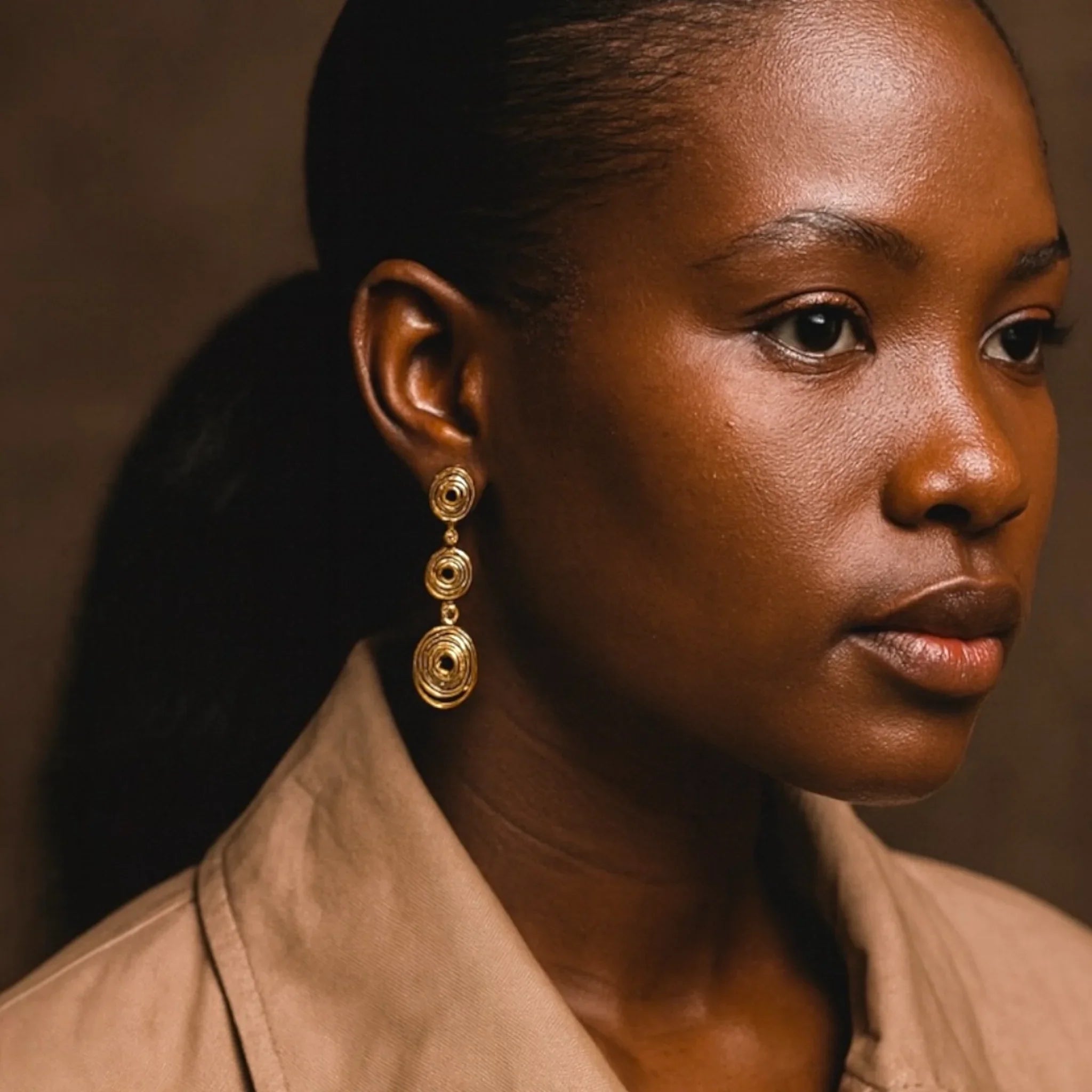 Woman wearing gold earrings with a neutral background